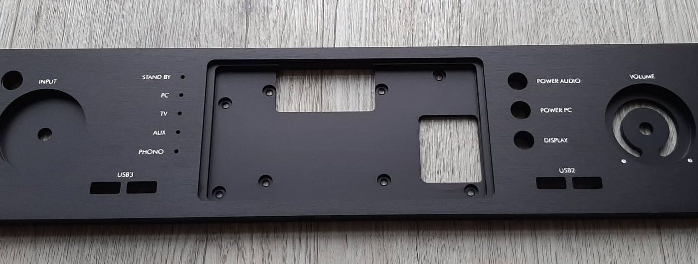 Black anodised aluminium front panel with engraved labels, cut-outs for a display and USB ports, and holes for buttons and a volume knob
